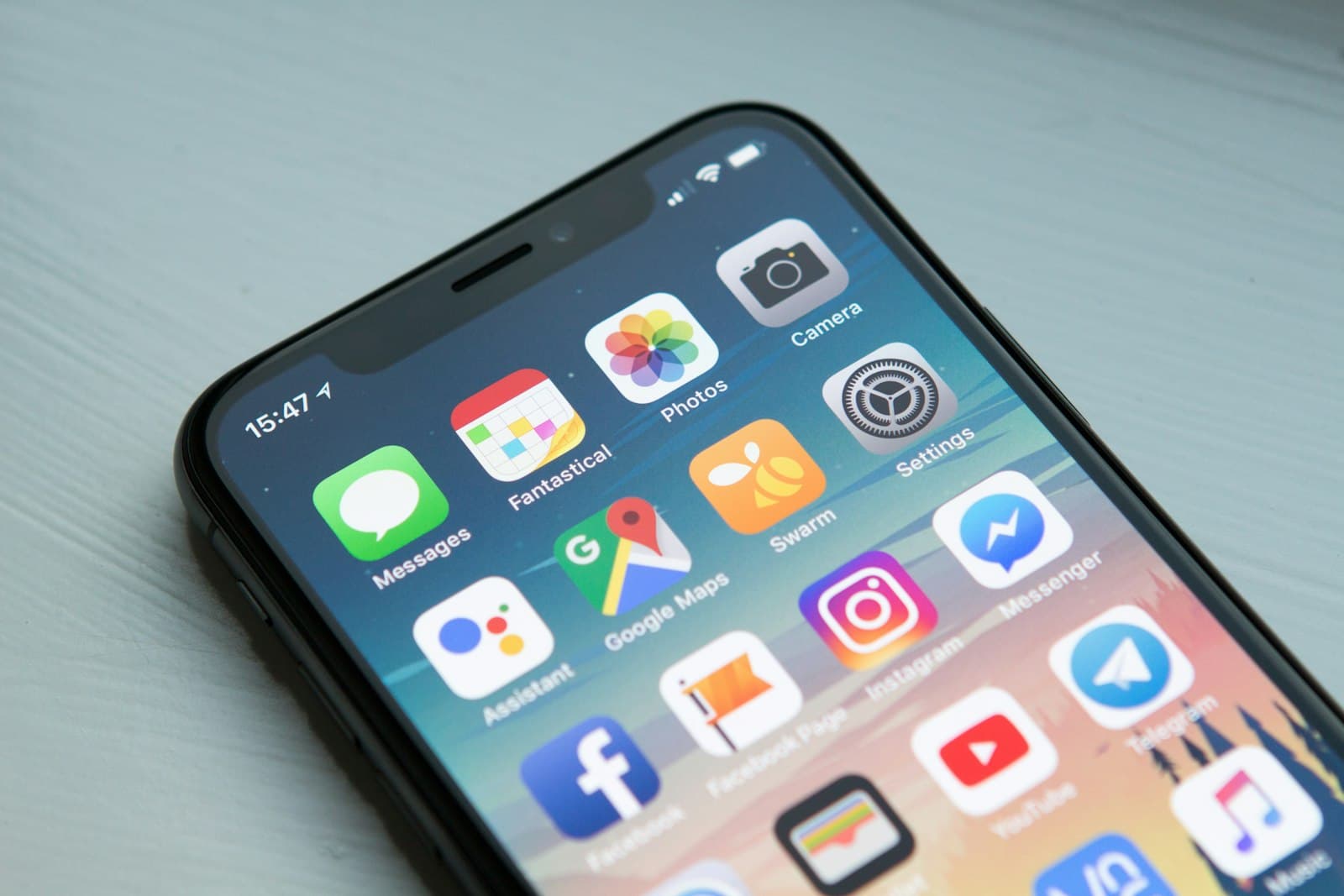 A close view of a smartphone home screen filled with app icons on a pale table. The phone fits a piece about motion on the screen people actually hold.