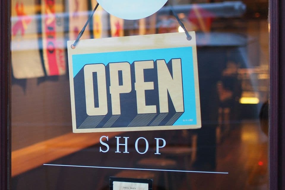 An OPEN sign hangs in a shop window, with the word SHOP printed on the glass. The open door only matters if the counter inside is easy to finish.