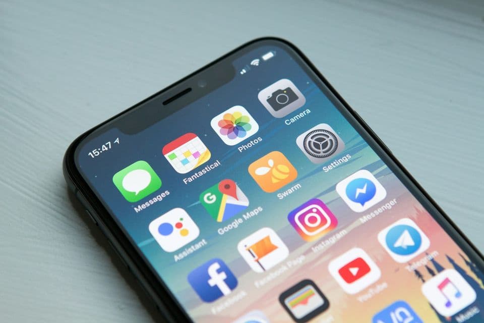 A close view of a smartphone home screen filled with app icons on a pale table. The phone fits a piece about motion on the screen people actually hold.