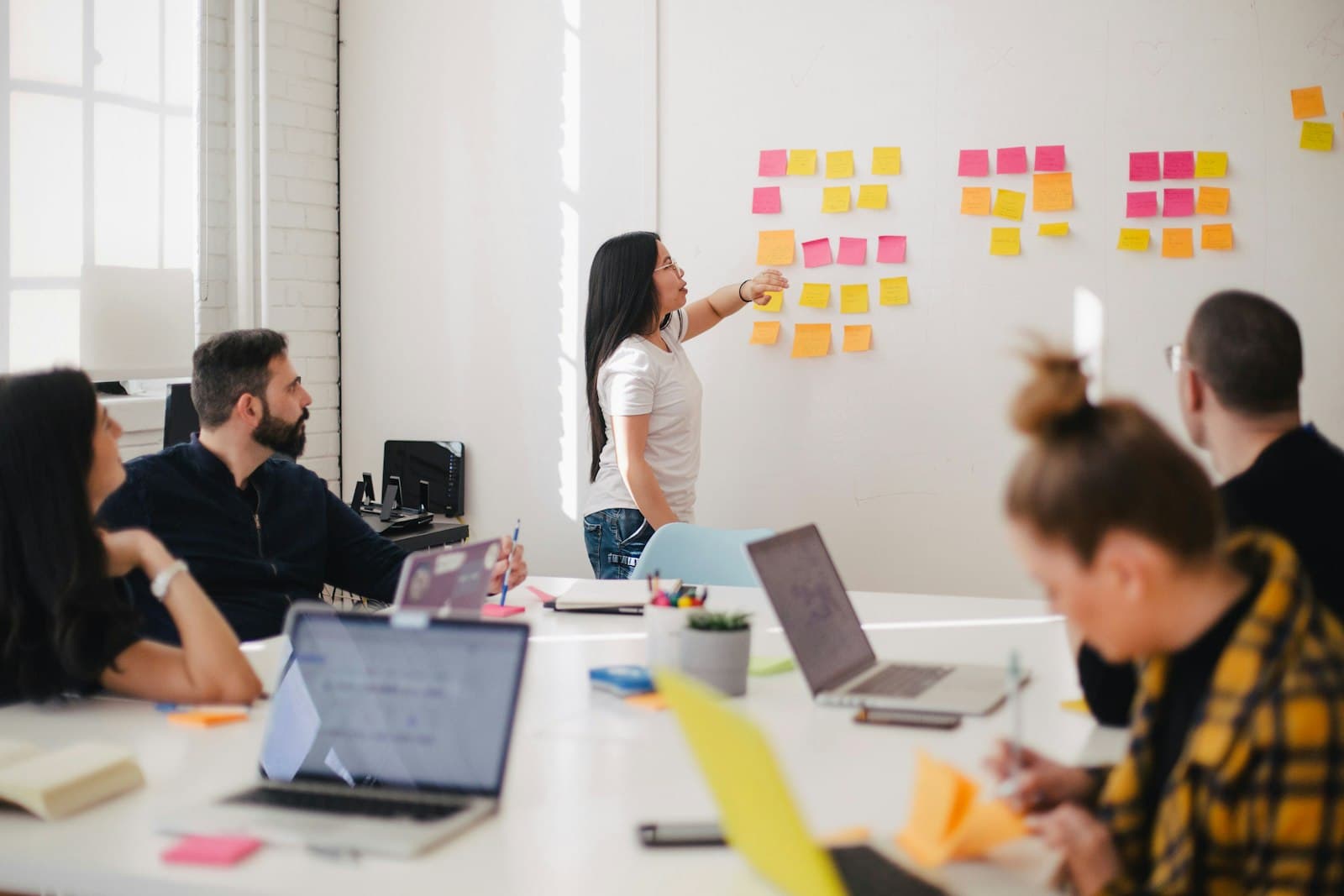 A workshop where one person points at colorful sticky notes while others sit with laptops, the room where access and ownership should be settled early.